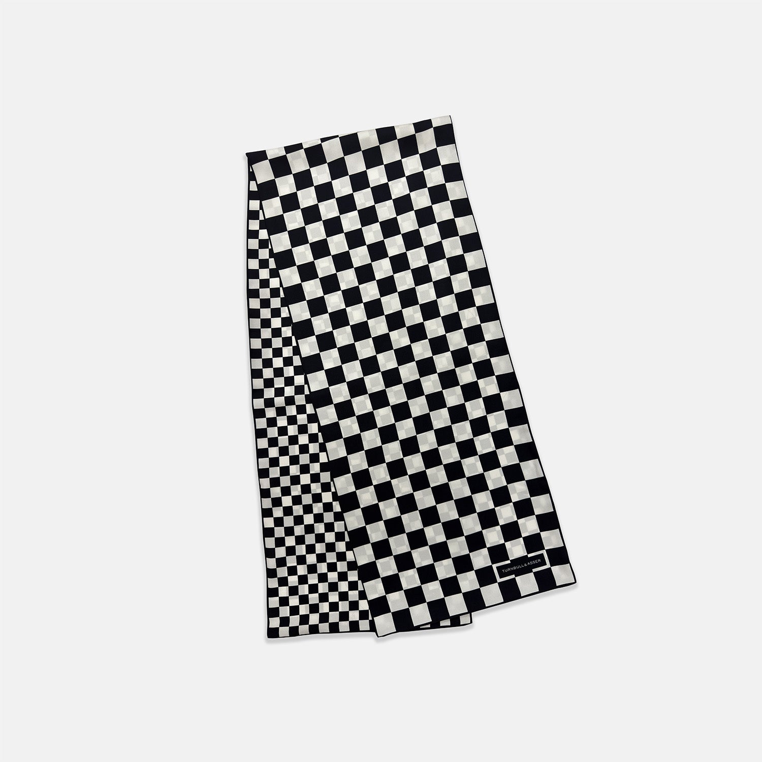 View 3 of product A Chequered Navy & White Scarf in Silk by Turnbull & Asser UK is displayed against a plain white background, showcasing its long, luxurious silk fabric with a striking navy and white checkered pattern.