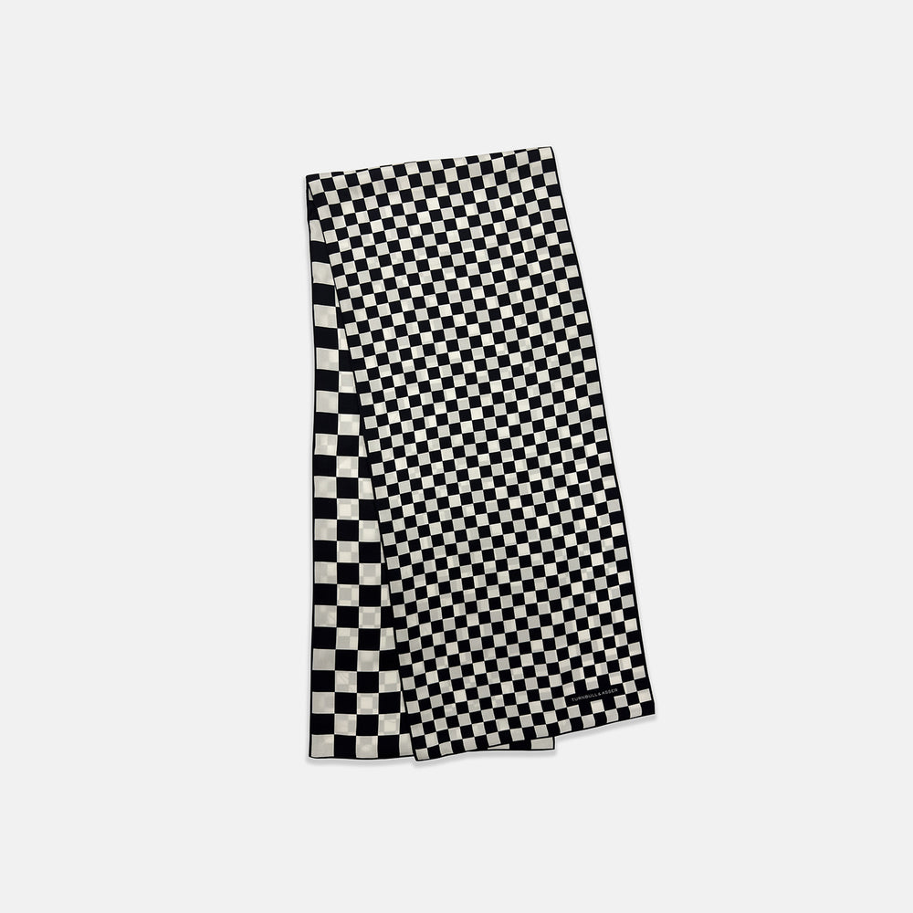 A Chequered Navy & White Scarf in Silk by Turnbull & Asser UK is displayed against a plain white background, showcasing its long, luxurious silk fabric with a striking navy and white checkered pattern.