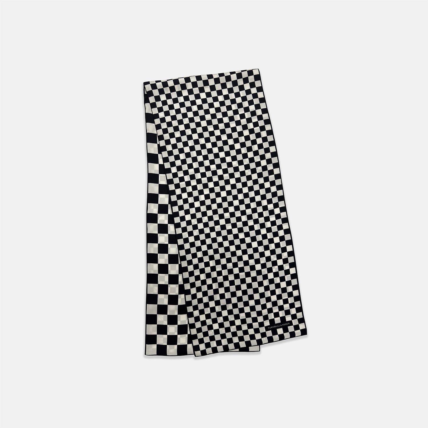 View 4 of product A Chequered Navy & White Scarf in Silk by Turnbull & Asser UK is displayed against a plain white background, showcasing its long, luxurious silk fabric with a striking navy and white checkered pattern.