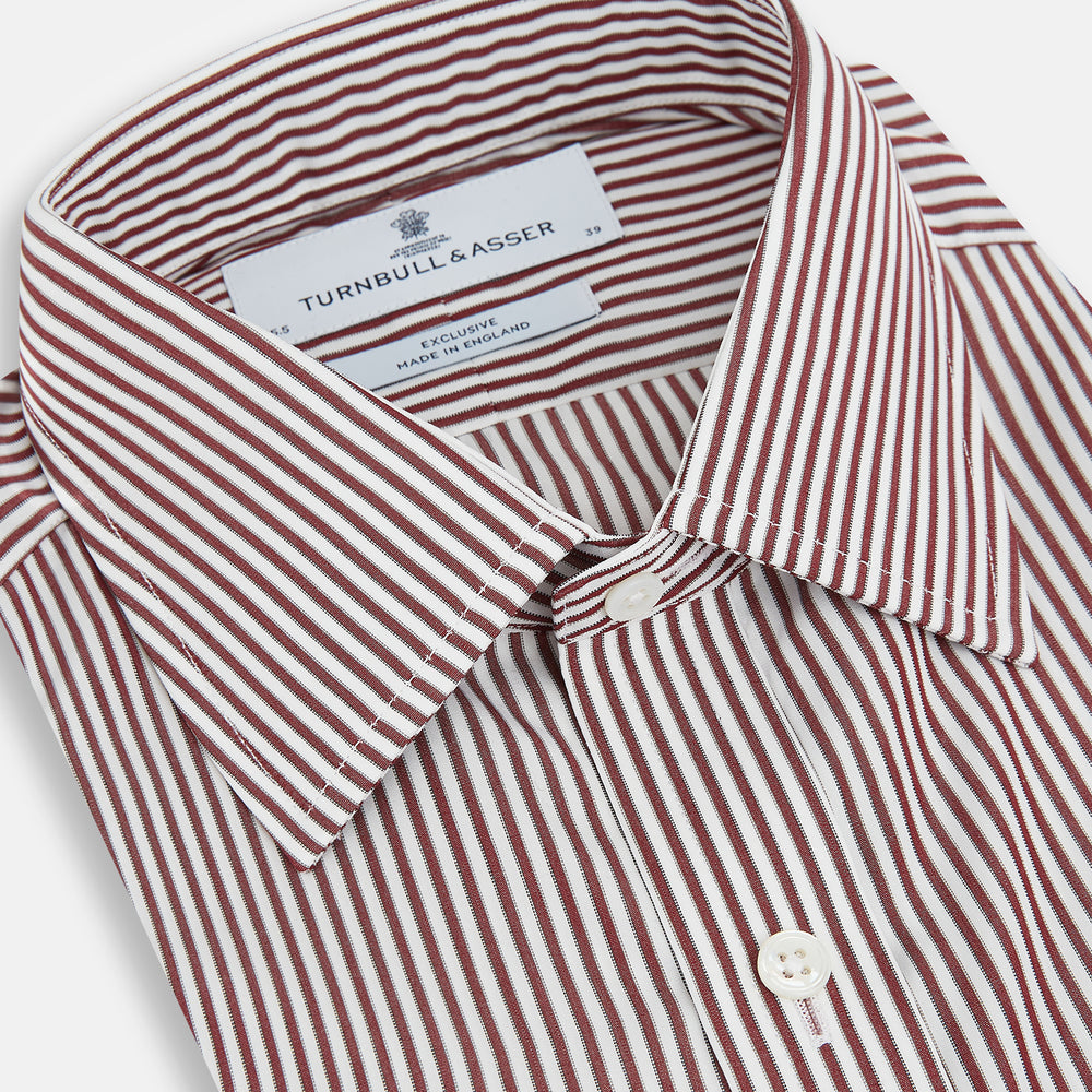 The Turnbull & Asser Burgundy Halo Stripe Winston Shirt features long sleeves, a classic T&A collar, buttoned cuffs, narrow vertical burgundy and white stripes, and is crafted from organic cotton. Displayed on a white background.