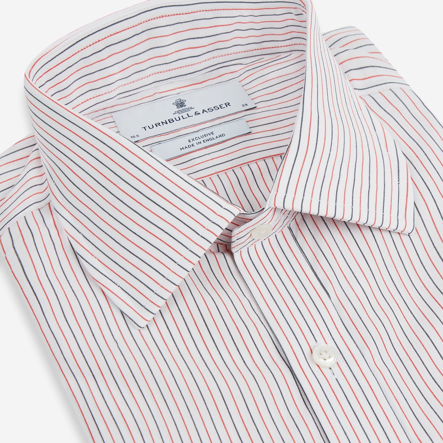 View 2 of product The Turnbull & Asser Red and Navy Pinstripe Mayfair Shirt, an organic cotton long-sleeve button-up with a collar, features thin vertical red and navy pinstripes on white, shown laid flat on a white surface.