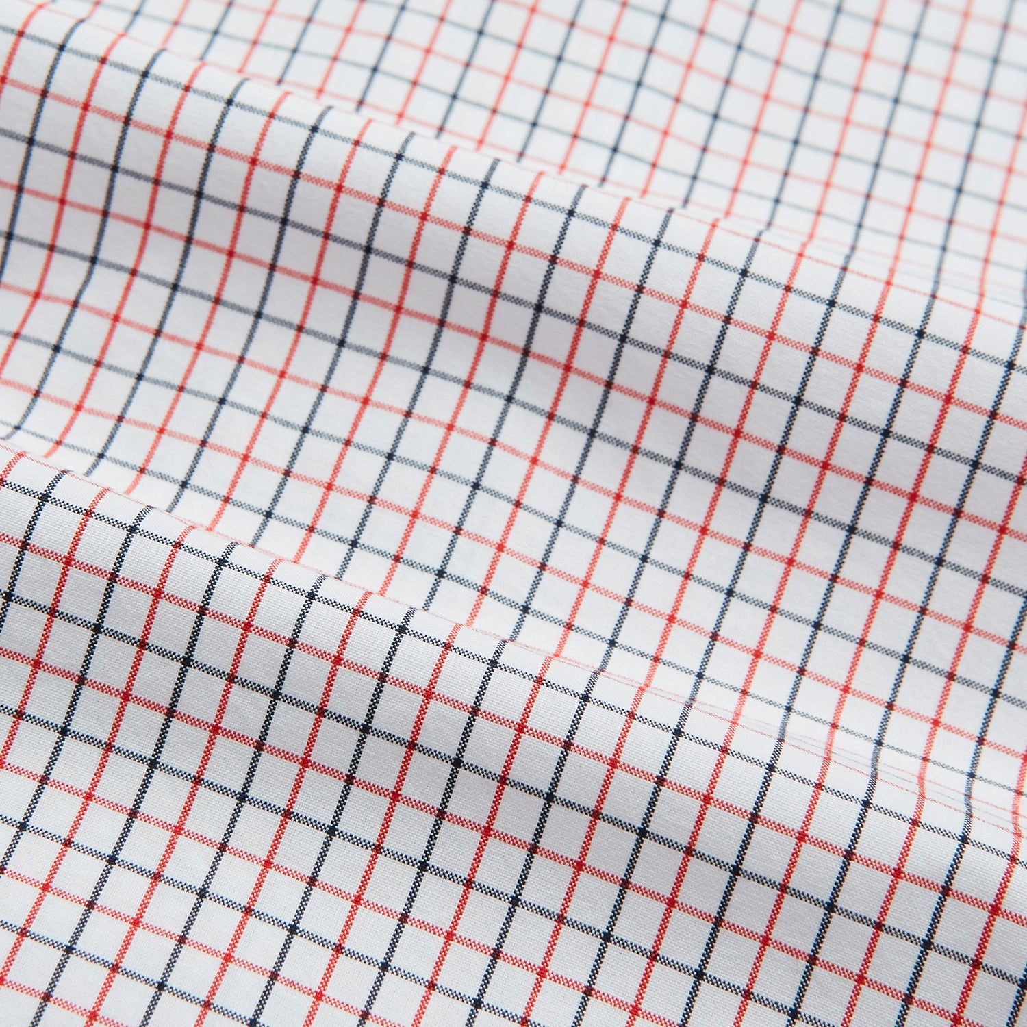 View 6 of product The Turnbull & Asser Red and Navy Graph Check Mayfair Shirt is a long-sleeved organic cotton button-up featuring a collar, buttoned cuffs, and a small red and navy check pattern, shown against a plain white background.