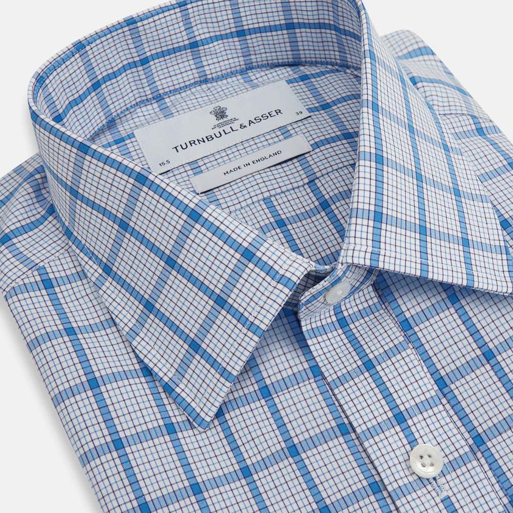 The Turnbull & Asser Blue Graph Overlay Check Mayfair Shirt features long sleeves, a spread collar, buttoned cuffs, and a blue and white plaid pattern, shown against a plain white background.