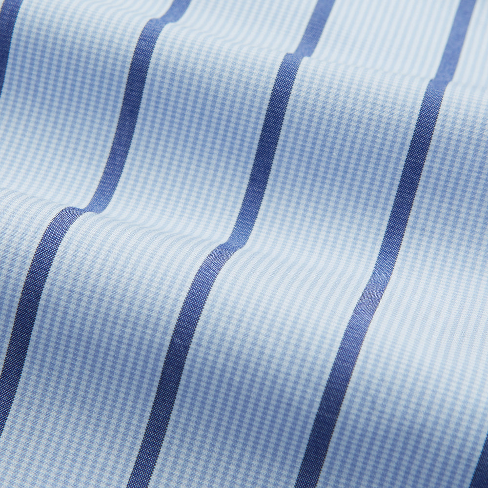 The Blue Track Stripe Mayfair Shirt by Turnbull & Asser features long sleeves, a T&A collar, vertical dark blue stripes on light blue organic cotton, and is shown against a plain white background.