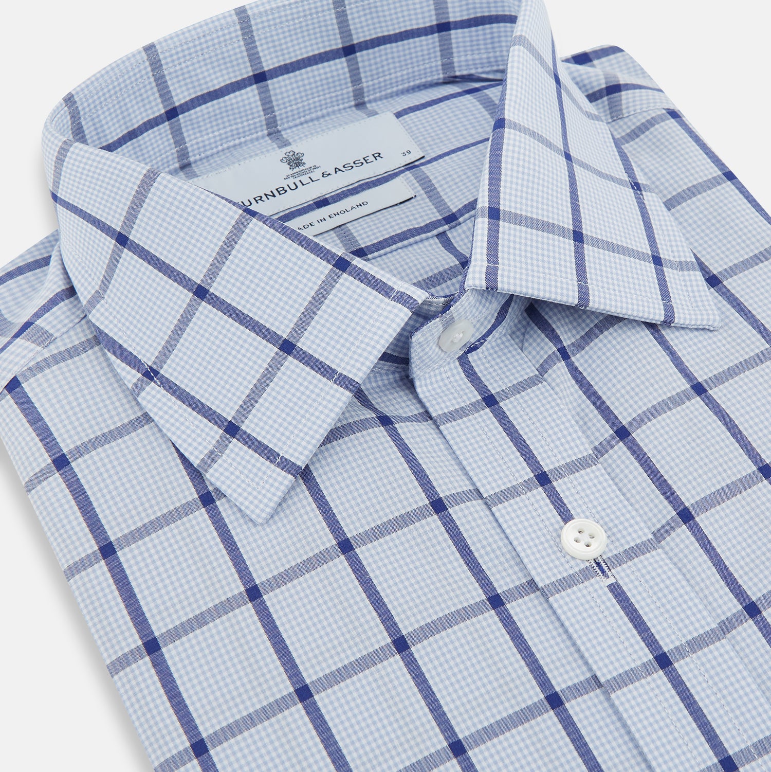 View 2 of product The Turnbull & Asser Navy Blue Windowpane Check Mayfair Shirt is a long-sleeved, organic cotton, button-up dress shirt with a classic collar and buttoned cuffs—white fabric with navy windowpane checks, ideal for any wardrobe capsule.