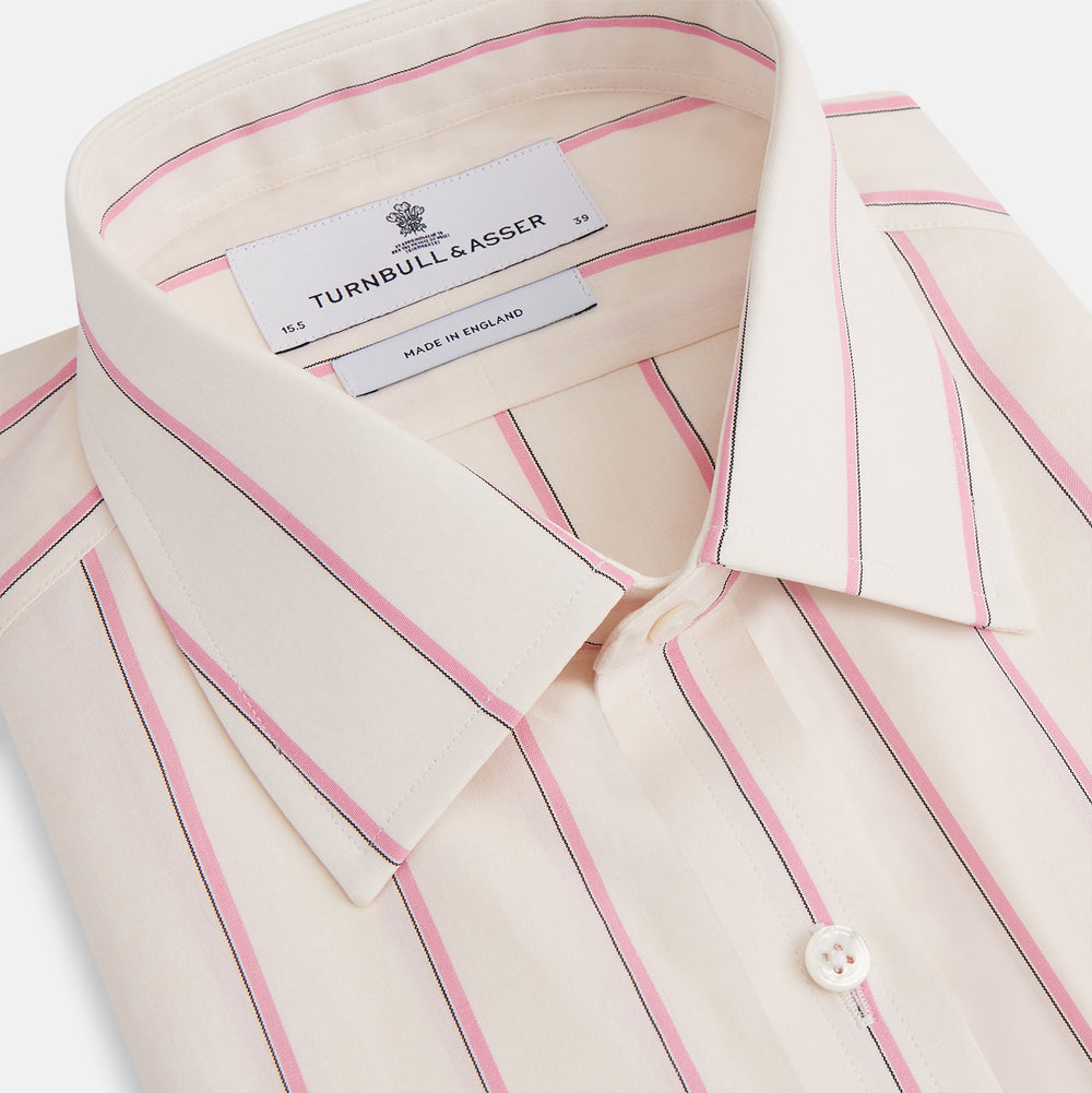 The Turnbull & Asser Pink Track Stripe Mayfair Shirt features long sleeves, a collar, and cream fabric with vertical pink stripes, crafted from breathable cotton and shown on a plain white background.