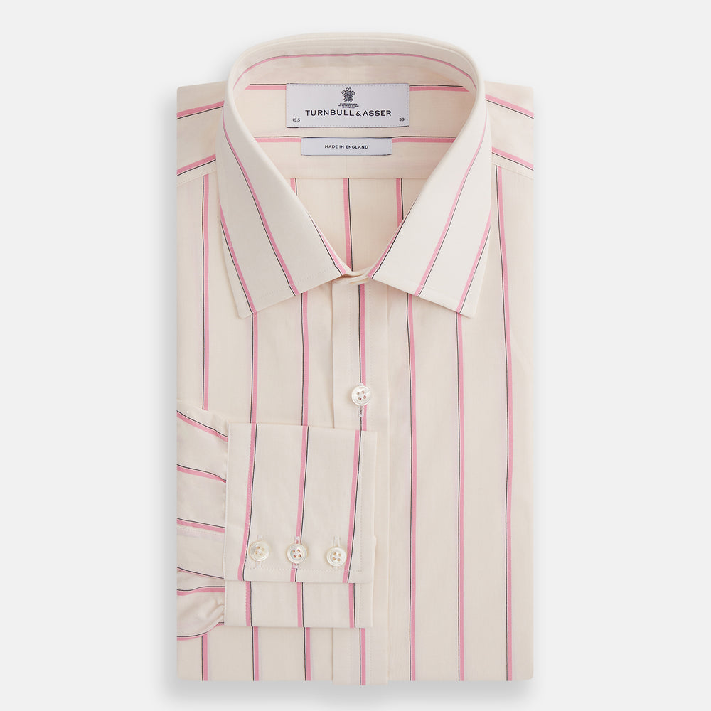 The Turnbull & Asser Pink Track Stripe Mayfair Shirt features long sleeves, a collar, and cream fabric with vertical pink stripes, crafted from breathable cotton and shown on a plain white background.