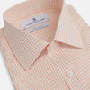 View 2 of product The Turnbull & Asser Orange Graph Check Mayfair Shirt features a classic T&A collar, long sleeves, buttoned cuffs, and a peach and white check pattern, shown against a white background.