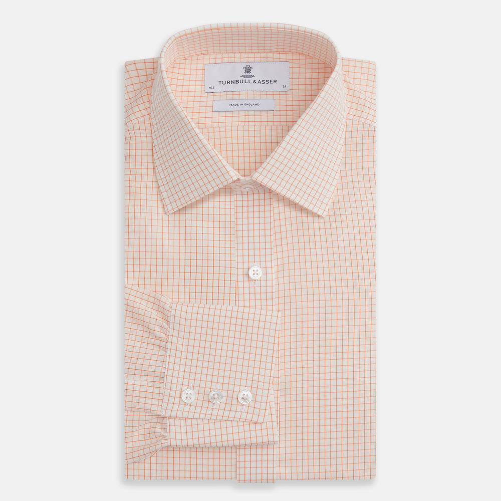 The Turnbull & Asser Orange Graph Check Mayfair Shirt features a classic T&A collar, long sleeves, buttoned cuffs, and a peach and white check pattern, shown against a white background.