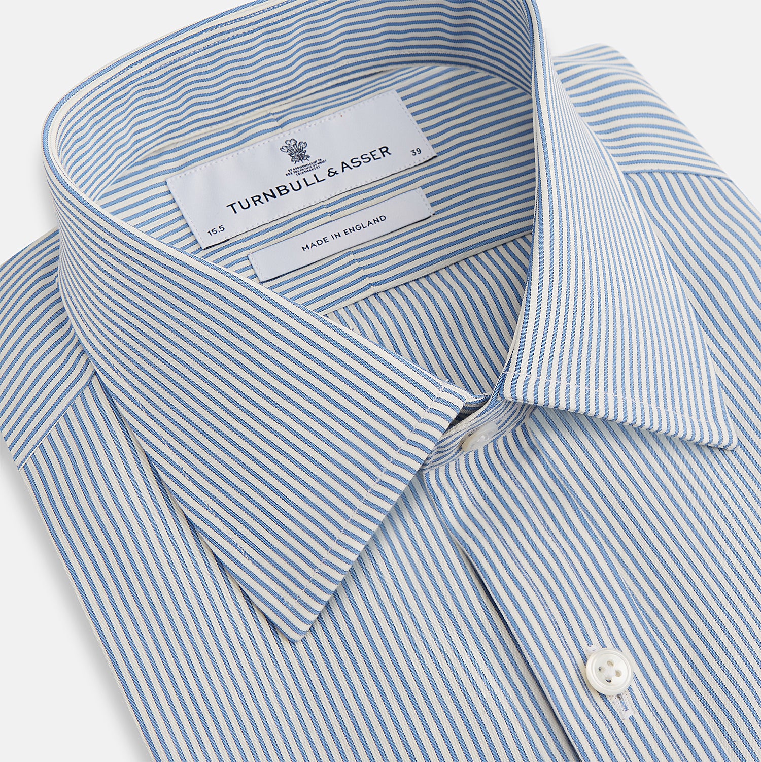 View 2 of product The Turnbull & Asser Blue and White Pencil Stripe Mayfair Shirt features breathable cotton, a standard collar, buttoned cuffs, and white buttons, shown laid flat on a white background.