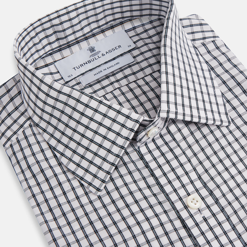 The Turnbull & Asser Midnight Blue Double Graph Check Mayfair Shirt features a pointed collar and buttoned cuffs. Crafted from breathable cotton, this stylish shirt ensures comfort and is shown against a white background.