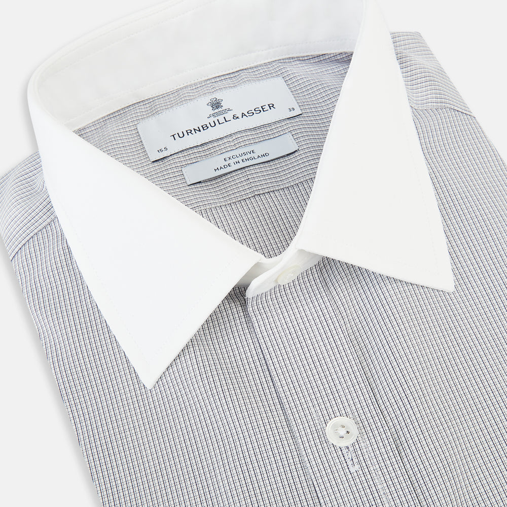 A Chequered White on Navy Regular Fit Shirt in Cotton by Turnbull & Asser UK, featuring a light gray finely checked pattern with a contrasting white collar and white French cuffs, long sleeves, buttoned up and displayed against a white background.