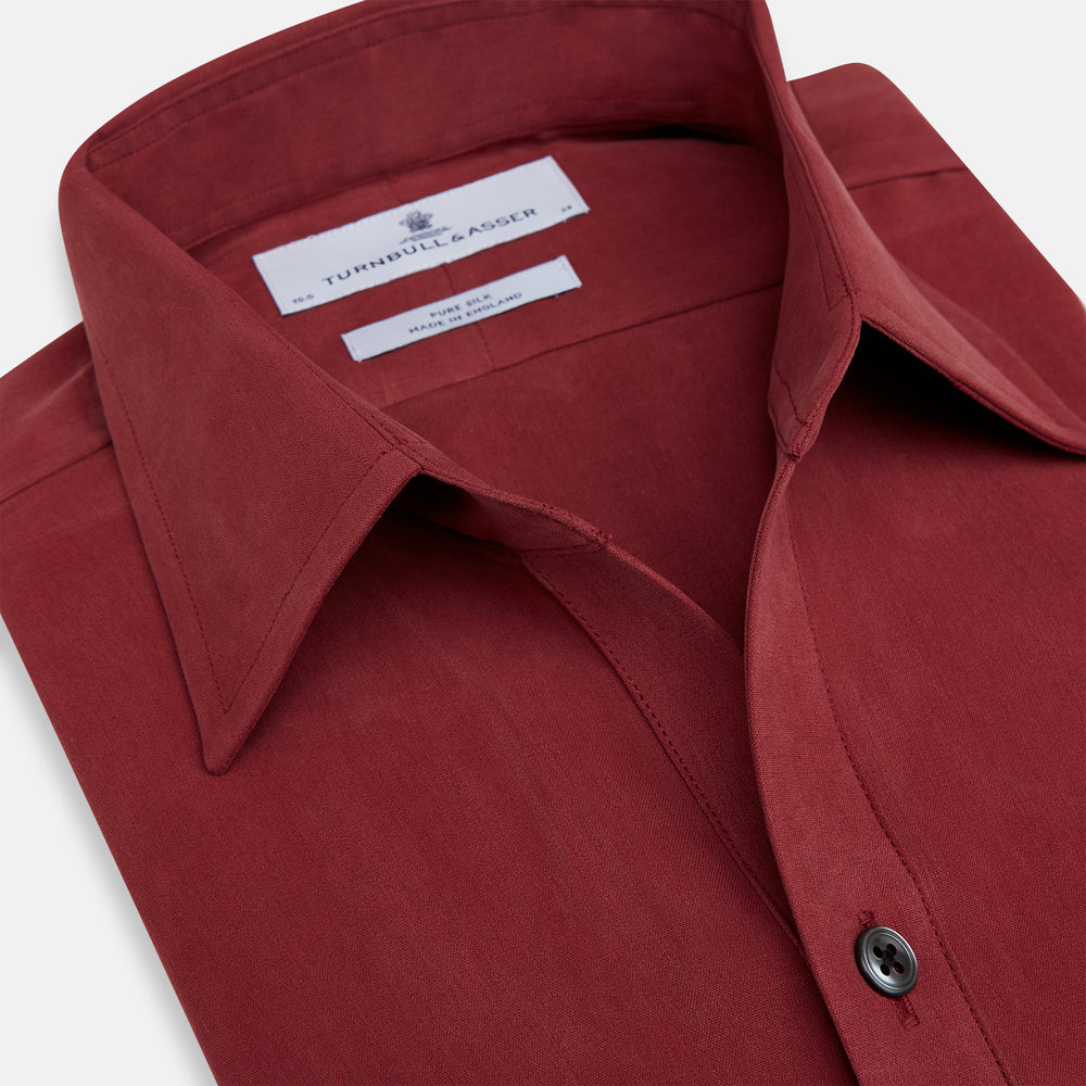 The Turnbull & Asser Burgundy Silk Chelsea Shirt is a long-sleeve, button-up top with a single chest pocket, shown on a white background.