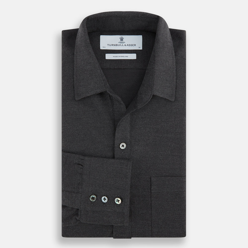 The Charcoal Chelsea Shirt by Turnbull & Asser is a long-sleeve, collared shirt in charcoal gray with a single chest pocket, offering smart-casual style, shown on a plain white background.