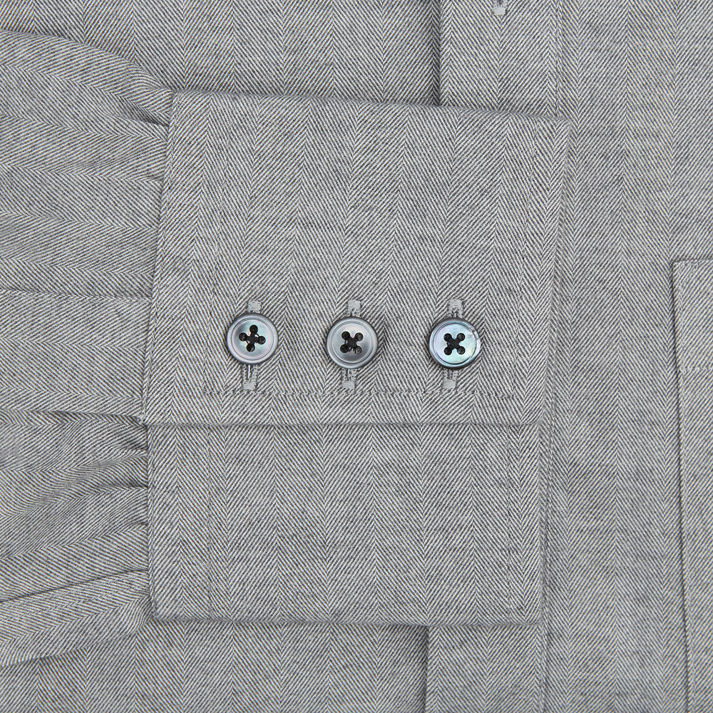 The Turnbull & Asser Grey Herringbone Chelsea Shirt features long sleeves, a chest pocket, classic collar, and buttoned cuffs, adding refined style to smart-casual outfits—shown here against a plain white background.