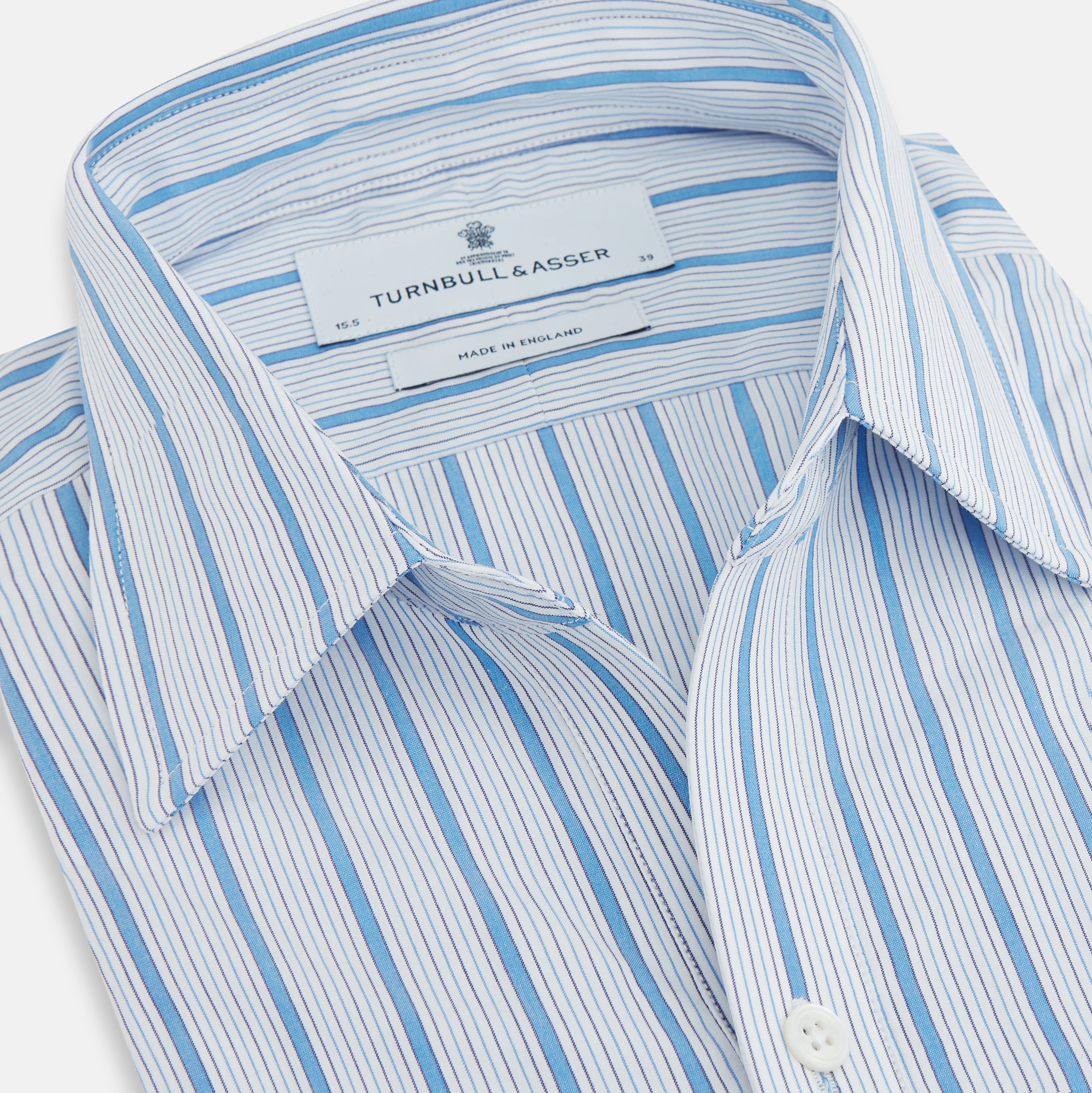 View 2 of product The Turnbull & Asser Blue Multi Track Stripe Chelsea Shirt features long sleeves, a light blue multi-stripe design, a chest pocket, open collar, and buttoned cuffs, shown laid flat on a white background.