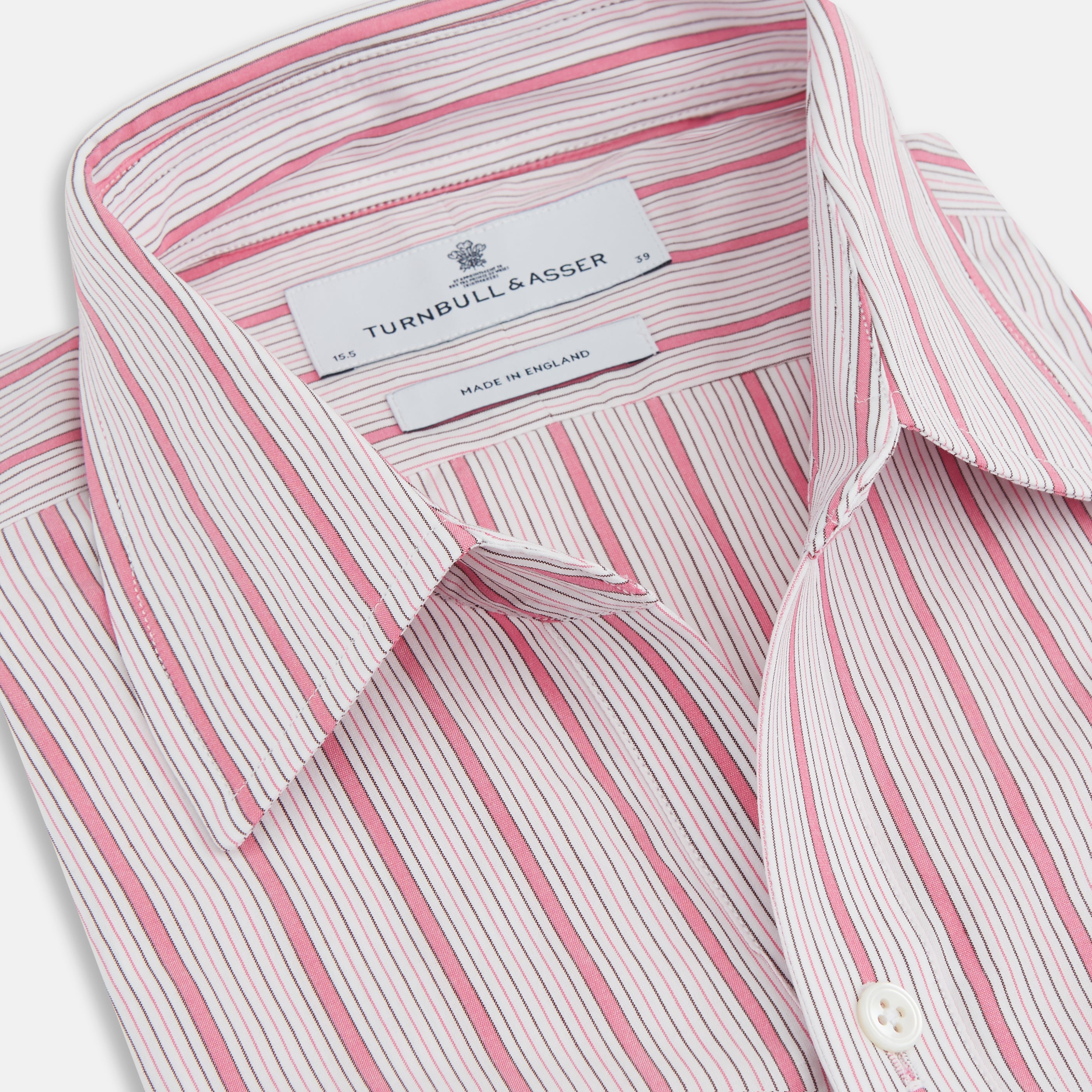 View 2 of product The Turnbull & Asser Pink Multi Track Stripe Chelsea Shirt features long sleeves, an open T&A collar, a left chest pocket, and buttoned cuffs, shown laid flat on a white background.
