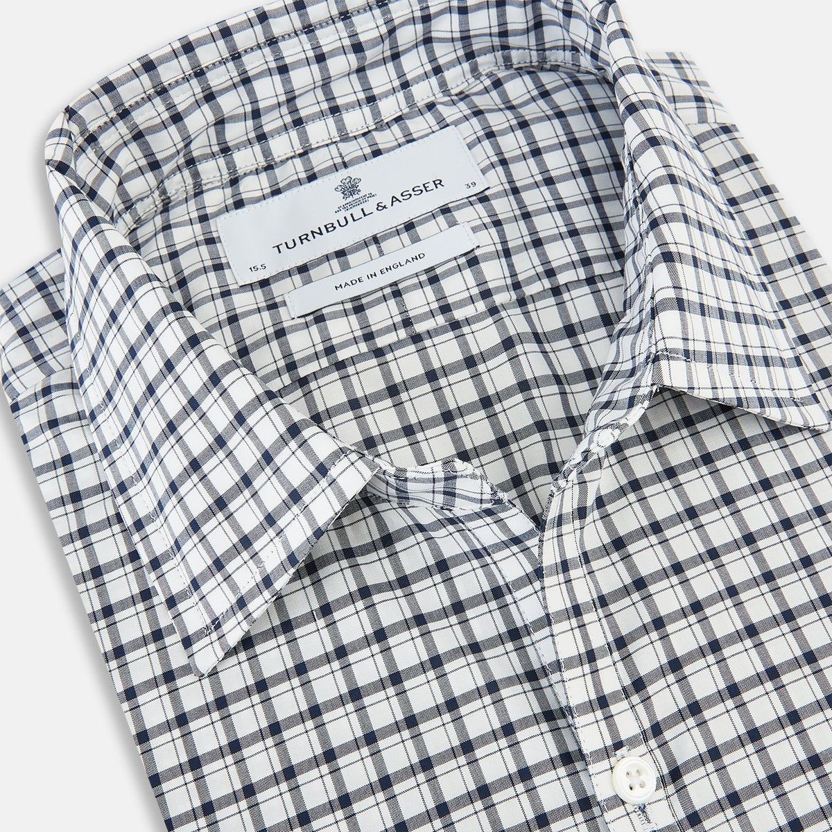 View 2 of product The Chequered Navy on White Windsor Regular Fit Shirt in Cotton by Turnbull & Asser UK features a Windsor collar and long sleeves, showcasing a crisp white background with a navy grid check pattern, displayed on a plain white surface.