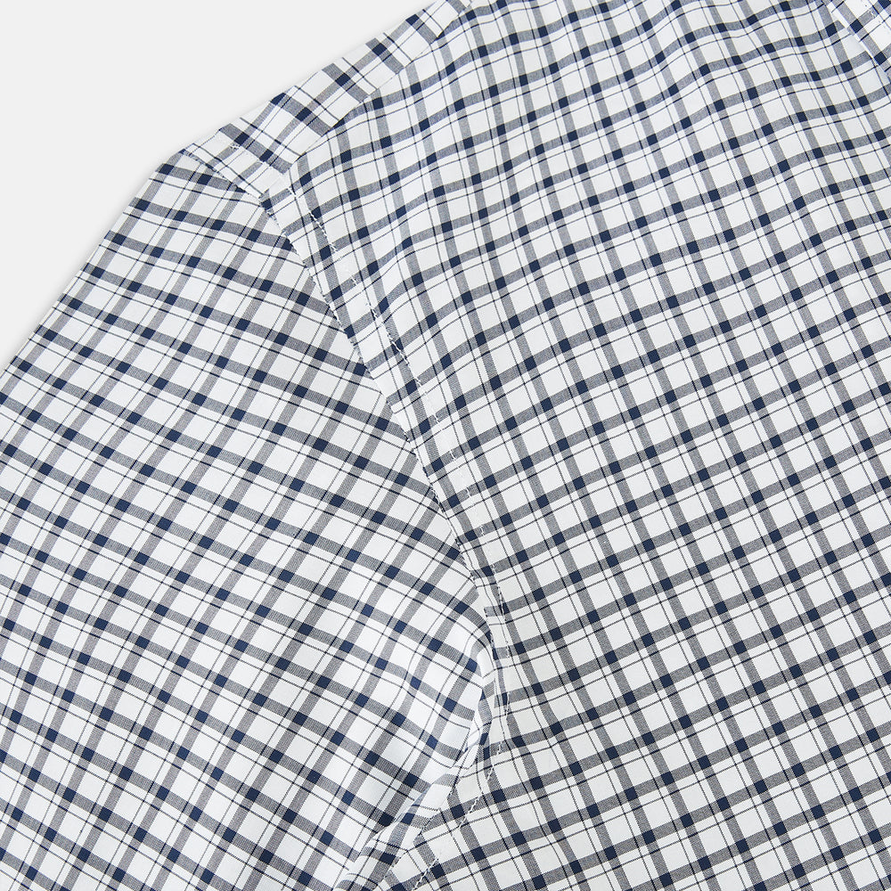 The Chequered Navy on White Windsor Regular Fit Shirt in Cotton by Turnbull & Asser UK features a Windsor collar and long sleeves, showcasing a crisp white background with a navy grid check pattern, displayed on a plain white surface.
