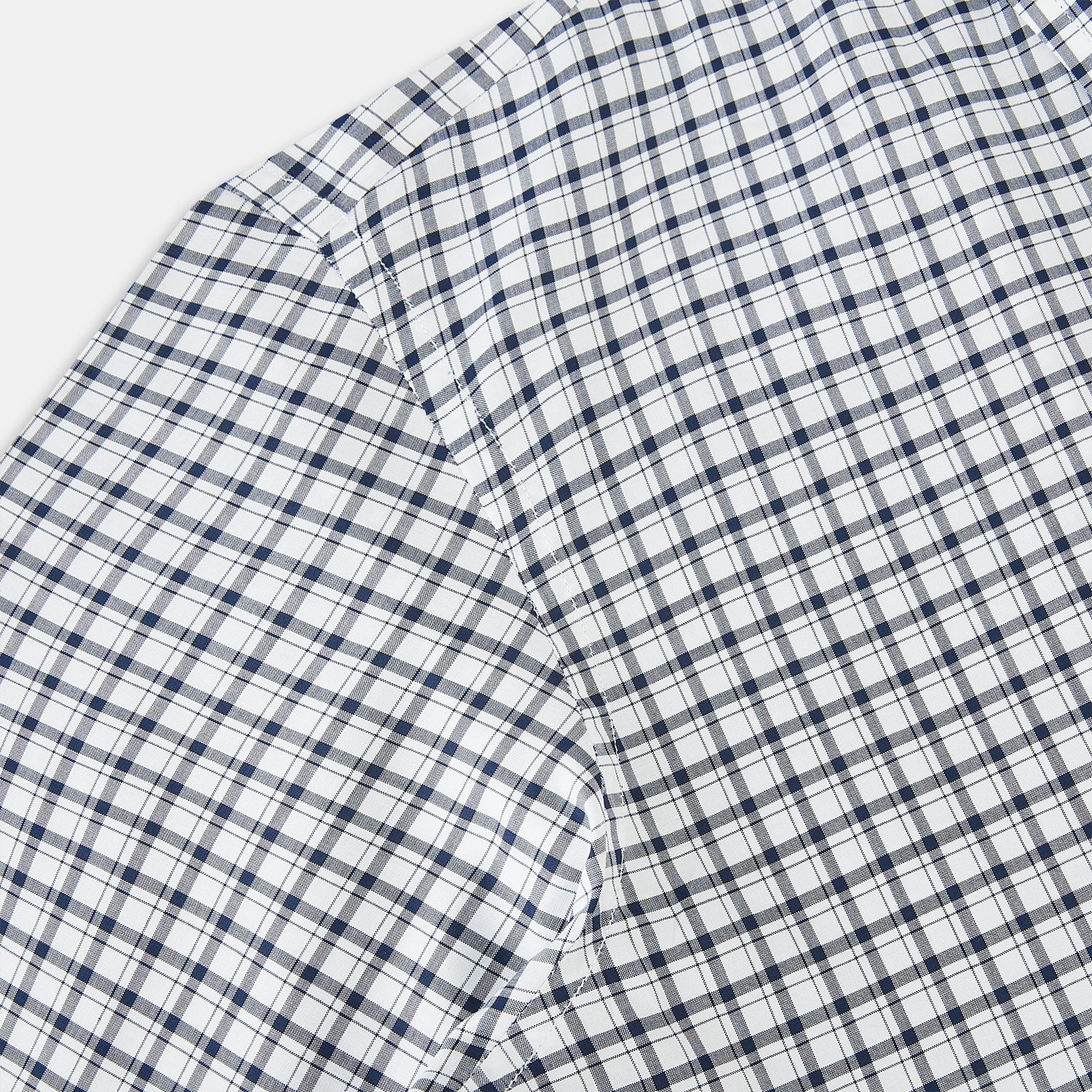 View 6 of product The Chequered Navy on White Windsor Regular Fit Shirt in Cotton by Turnbull & Asser UK features a Windsor collar and long sleeves, showcasing a crisp white background with a navy grid check pattern, displayed on a plain white surface.