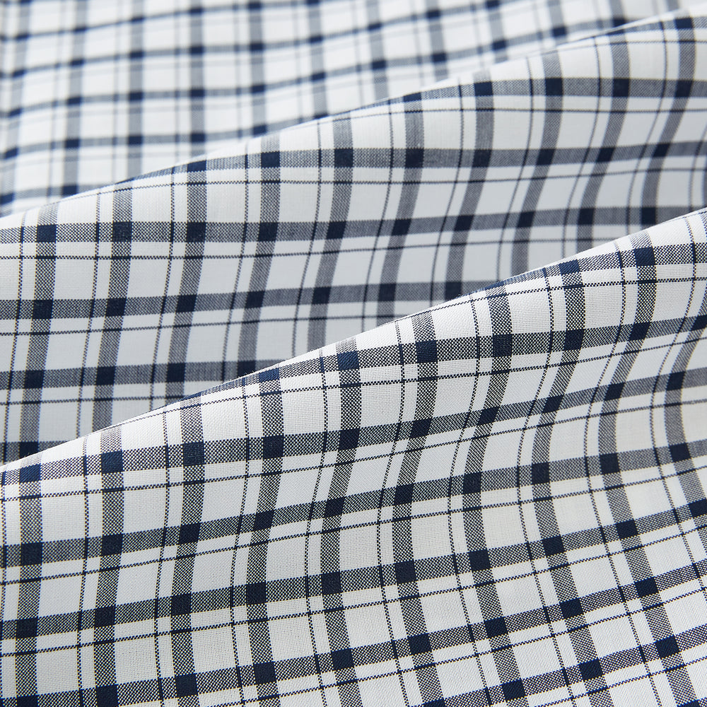 The Chequered Navy on White Windsor Regular Fit Shirt in Cotton by Turnbull & Asser UK features a Windsor collar and long sleeves, showcasing a crisp white background with a navy grid check pattern, displayed on a plain white surface.