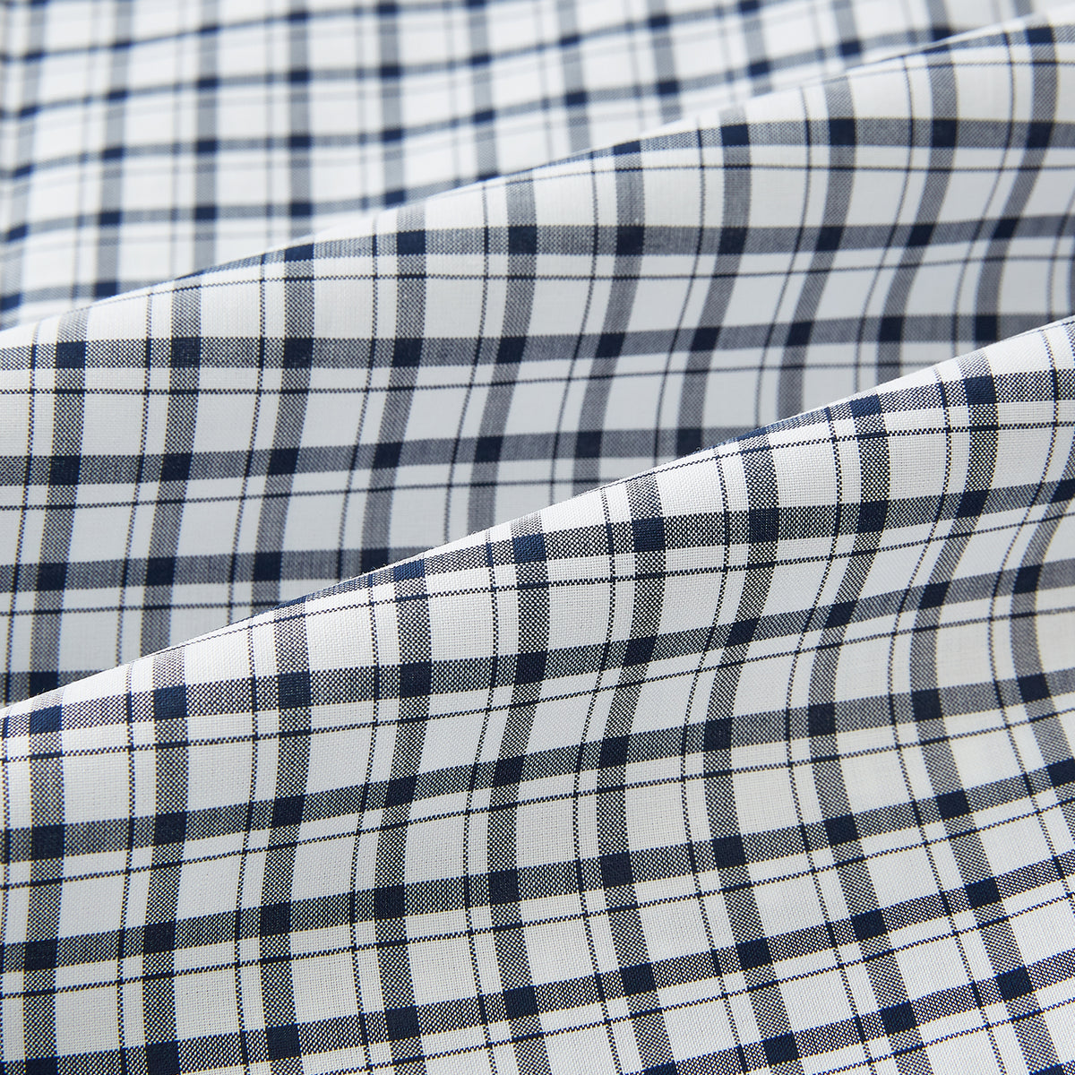 View 8 of product The Chequered Navy on White Windsor Regular Fit Shirt in Cotton by Turnbull & Asser UK features a Windsor collar and long sleeves, showcasing a crisp white background with a navy grid check pattern, displayed on a plain white surface.