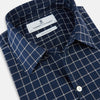 View 2 of product The Turnbull & Asser UK White Check on Navy Windsor Shirt features an open collar, button cuffs, and cuffed long sleeves. Showcased against a white background, this shirt presents a navy base adorned with a white grid pattern.