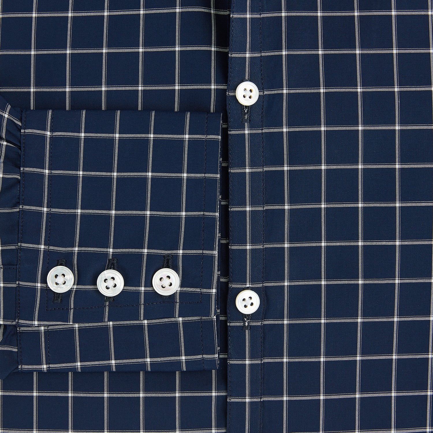 View 4 of product The Turnbull & Asser UK White Check on Navy Windsor Shirt features an open collar, button cuffs, and cuffed long sleeves. Showcased against a white background, this shirt presents a navy base adorned with a white grid pattern.