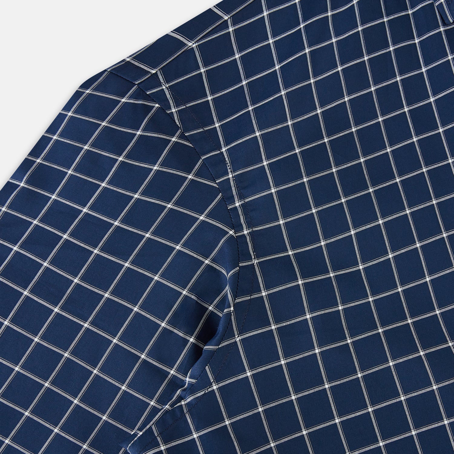 View 6 of product The Turnbull & Asser UK White Check on Navy Windsor Shirt features an open collar, button cuffs, and cuffed long sleeves. Showcased against a white background, this shirt presents a navy base adorned with a white grid pattern.