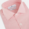 View 2 of product The Turnbull & Asser UK CORAL COTTON MINI CHECKED SHIRT is a light pink long-sleeve button-up shirt with a Kent collar, white buttons, and three-button cuffs, shown on a plain white background.