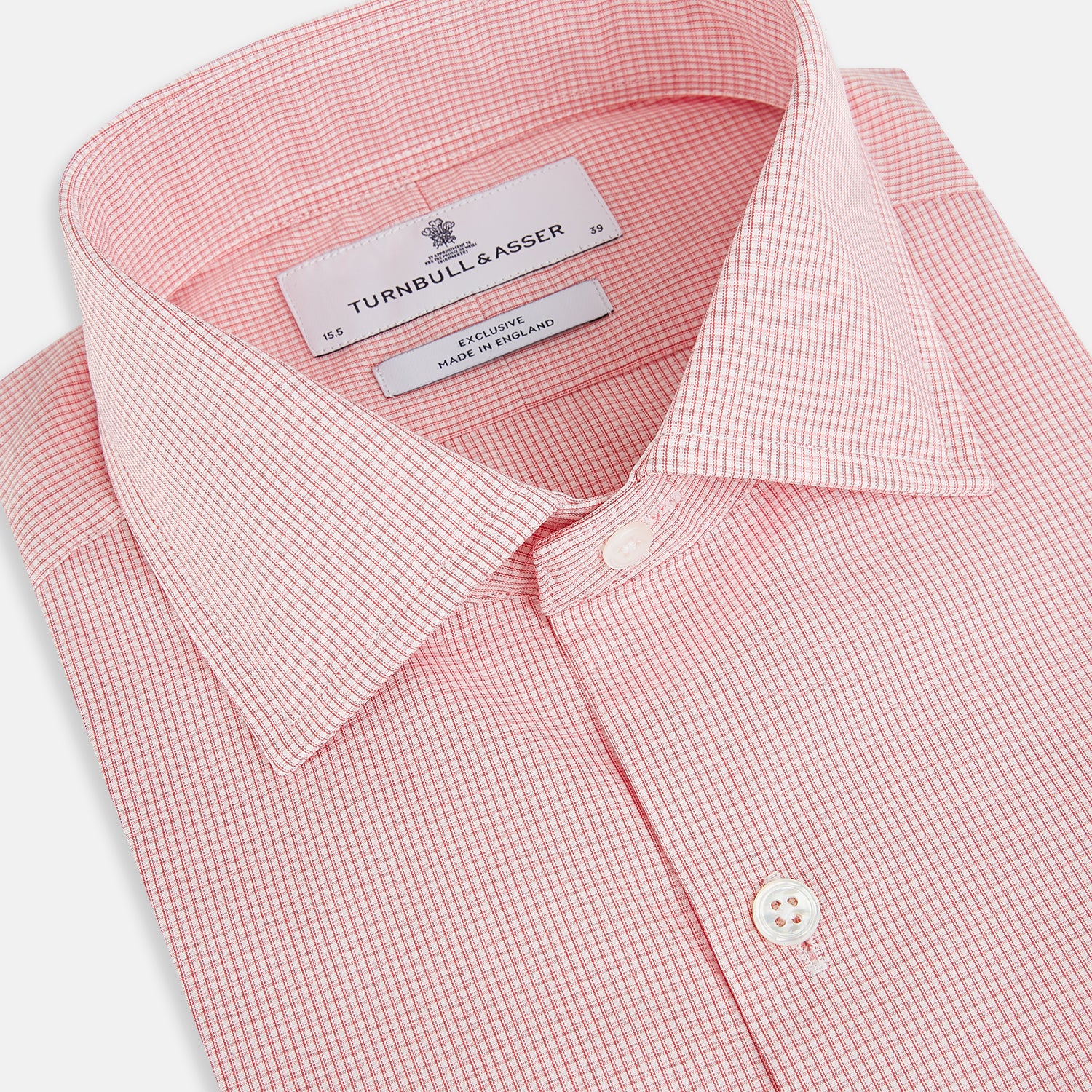 View 2 of product The Turnbull & Asser UK CORAL COTTON MINI CHECKED SHIRT is a light pink long-sleeve button-up shirt with a Kent collar, white buttons, and three-button cuffs, shown on a plain white background.