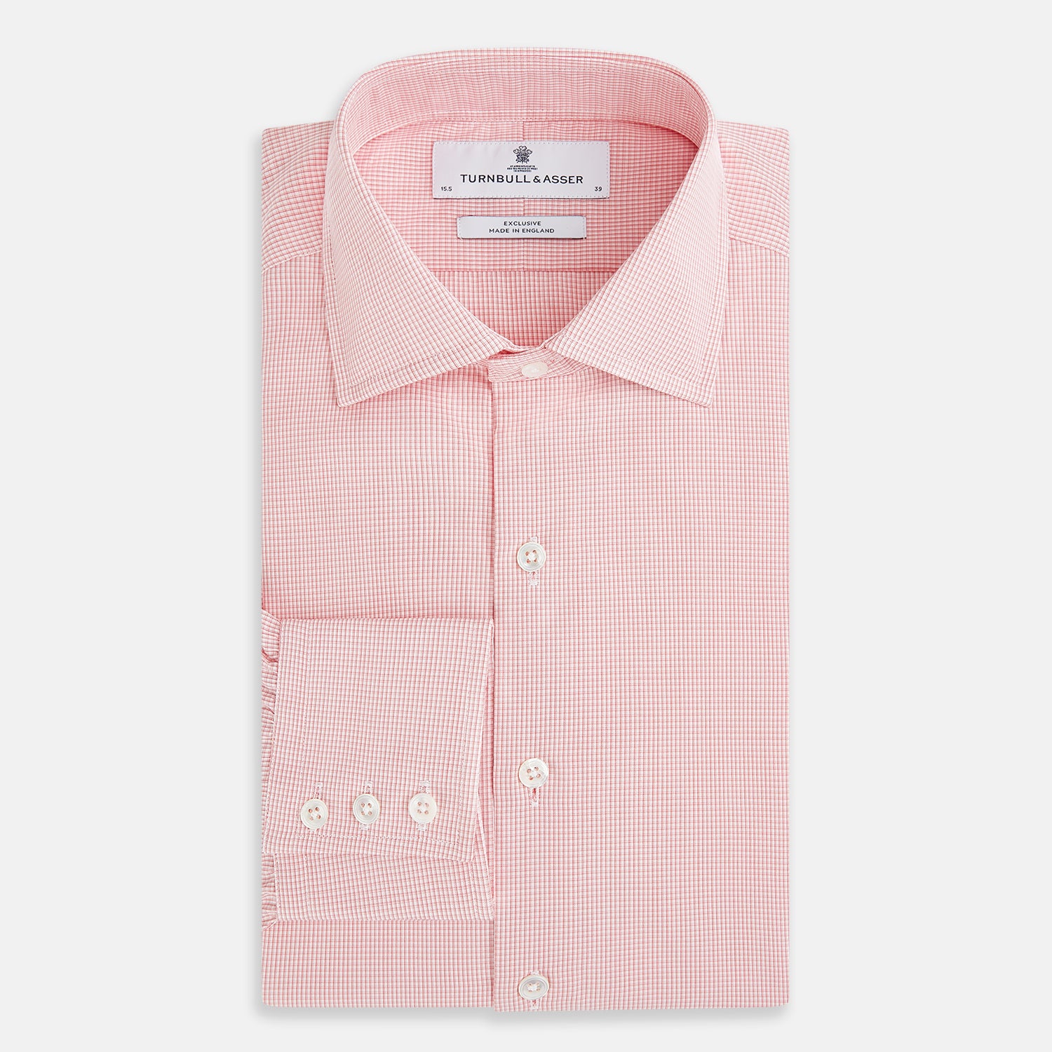 View 5 of product The Turnbull & Asser UK CORAL COTTON MINI CHECKED SHIRT is a light pink long-sleeve button-up shirt with a Kent collar, white buttons, and three-button cuffs, shown on a plain white background.