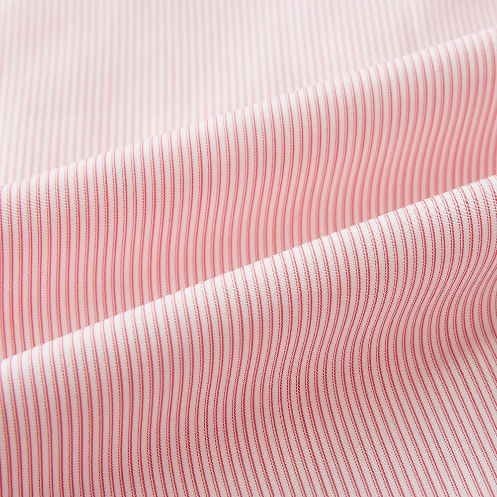 The Fine Striped Coral on White Tailored Fit Shirt in Cotton by Turnbull & Asser UK is a light pink long-sleeve button-up dress shirt with a collar, featuring subtle coral stripe detailing, displayed flat against a white background.