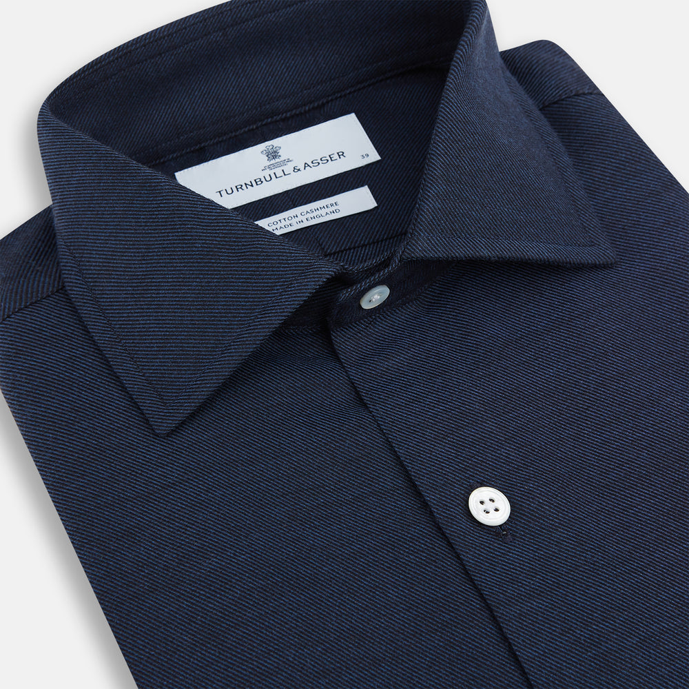 The Turnbull & Asser Tailored Fit Navy Cotton Cashmere Belgravia Shirt features a classic collar, white buttons, and long sleeves, shown on a white background.
