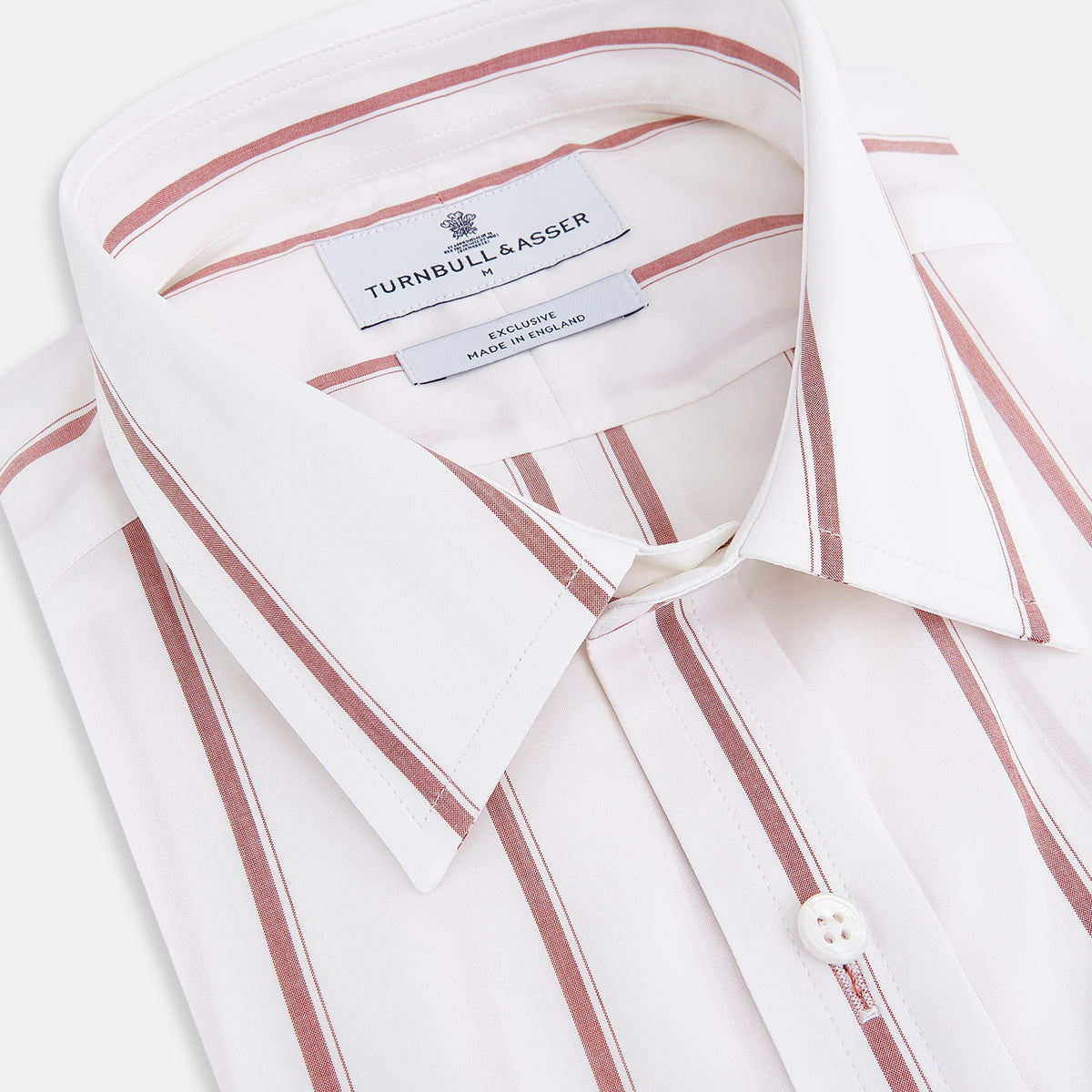 View 2 of product The Turnbull & Asser UK Track Striped Red on White Weekend Fit Shirt in Cotton features bold dark red stripes on a crisp white base, with long sleeves, a derby collar, front chest pocket, and buttoned cuffs, laid flat on a white background for a timeless men’s dress shirt aesthetic.