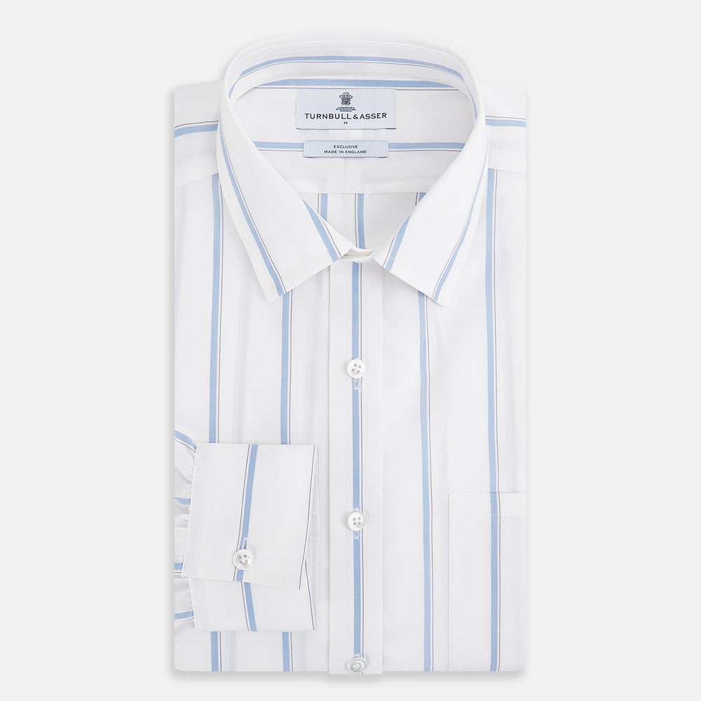 The Turnbull & Asser UK Track Striped Blue on White Weekend Fit Shirt in Cotton is a long-sleeve, button-up shirt featuring blue stripes on premium white Italian cotton, a Derby collar, and a chest pocket, elegantly laid flat against a white background.