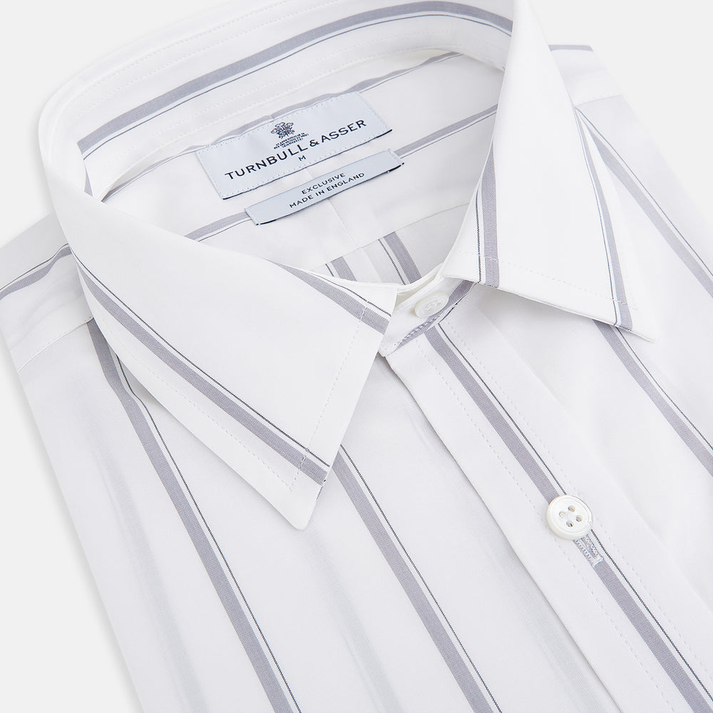 Introducing the Track Striped Grey on White Weekend Fit Shirt in Cotton by Turnbull & Asser UK—a men’s long-sleeve dress shirt crafted from crisp white cotton, featuring vertical grey stripes, a button-down front, derby collar, cuffs, and a chest pocket. The shirt is displayed laid flat on a white surface.
