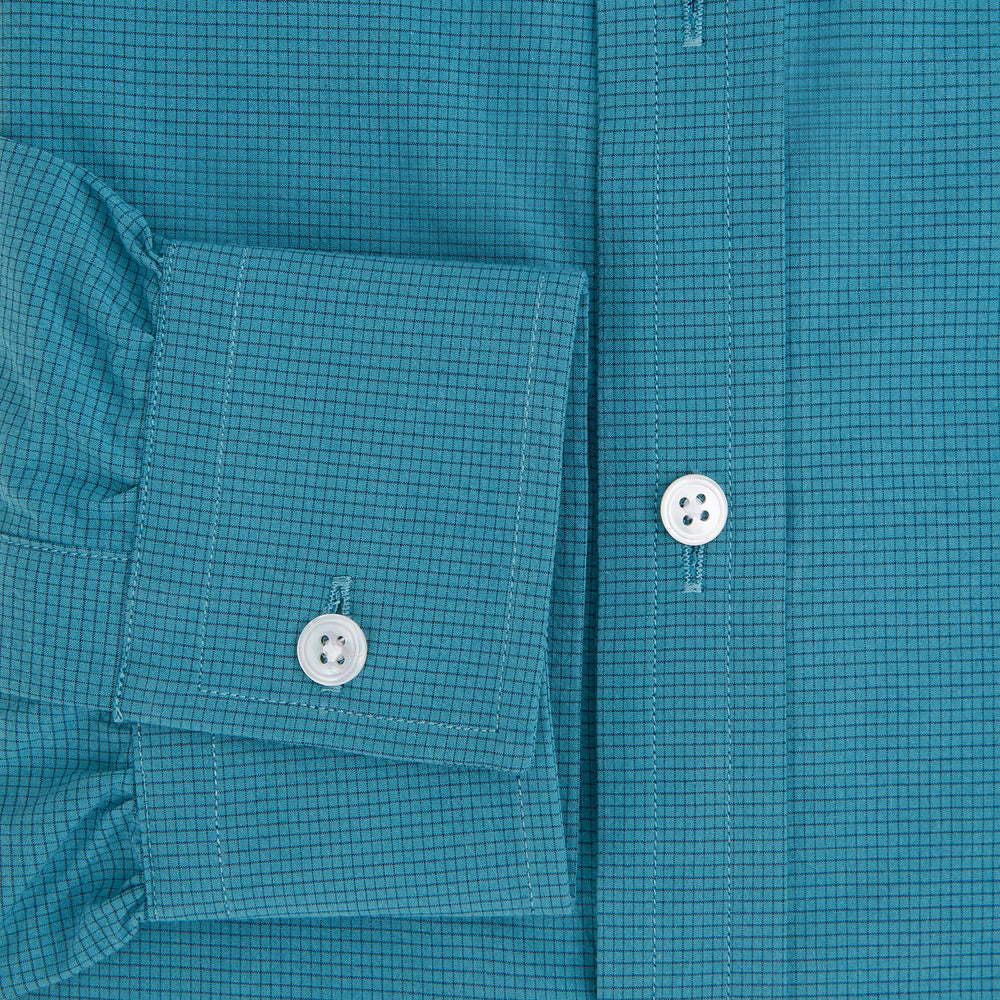 Here’s a rewritten version using your product data: The Turnbull & Asser UK Fine Checked Turquoise Blue Weekend Fit Shirt in Cotton is a men’s long-sleeve button-up, featuring a chest pocket, white buttons, and a pointed collar, shown laid flat against a white background.