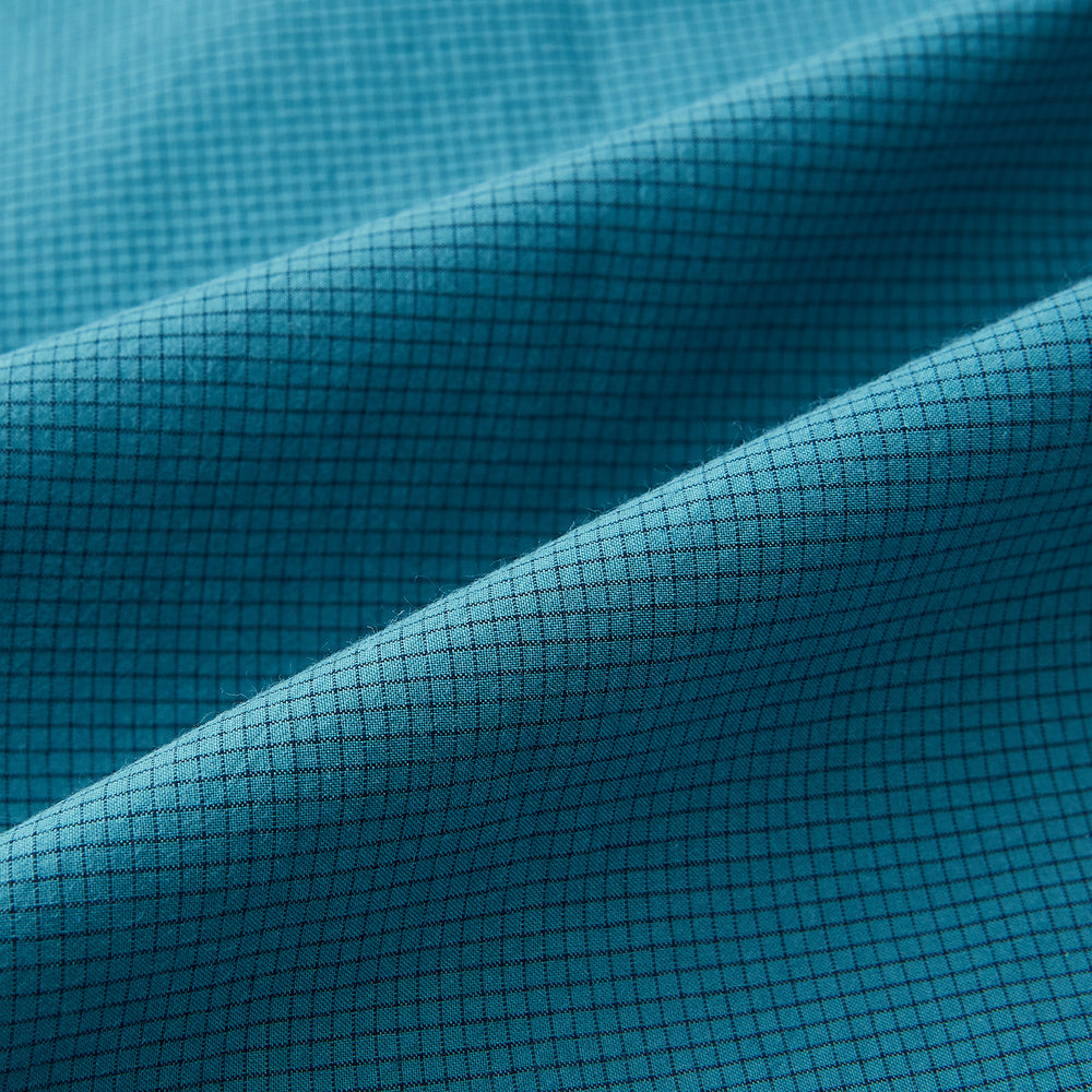 Here’s a rewritten version using your product data: The Turnbull & Asser UK Fine Checked Turquoise Blue Weekend Fit Shirt in Cotton is a men’s long-sleeve button-up, featuring a chest pocket, white buttons, and a pointed collar, shown laid flat against a white background.