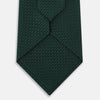 View 3 of product A Dark Green Grenadine Silk Tie by Turnbull & Asser UK, featuring a textured knit, is rolled up at one end and displayed on a white background.