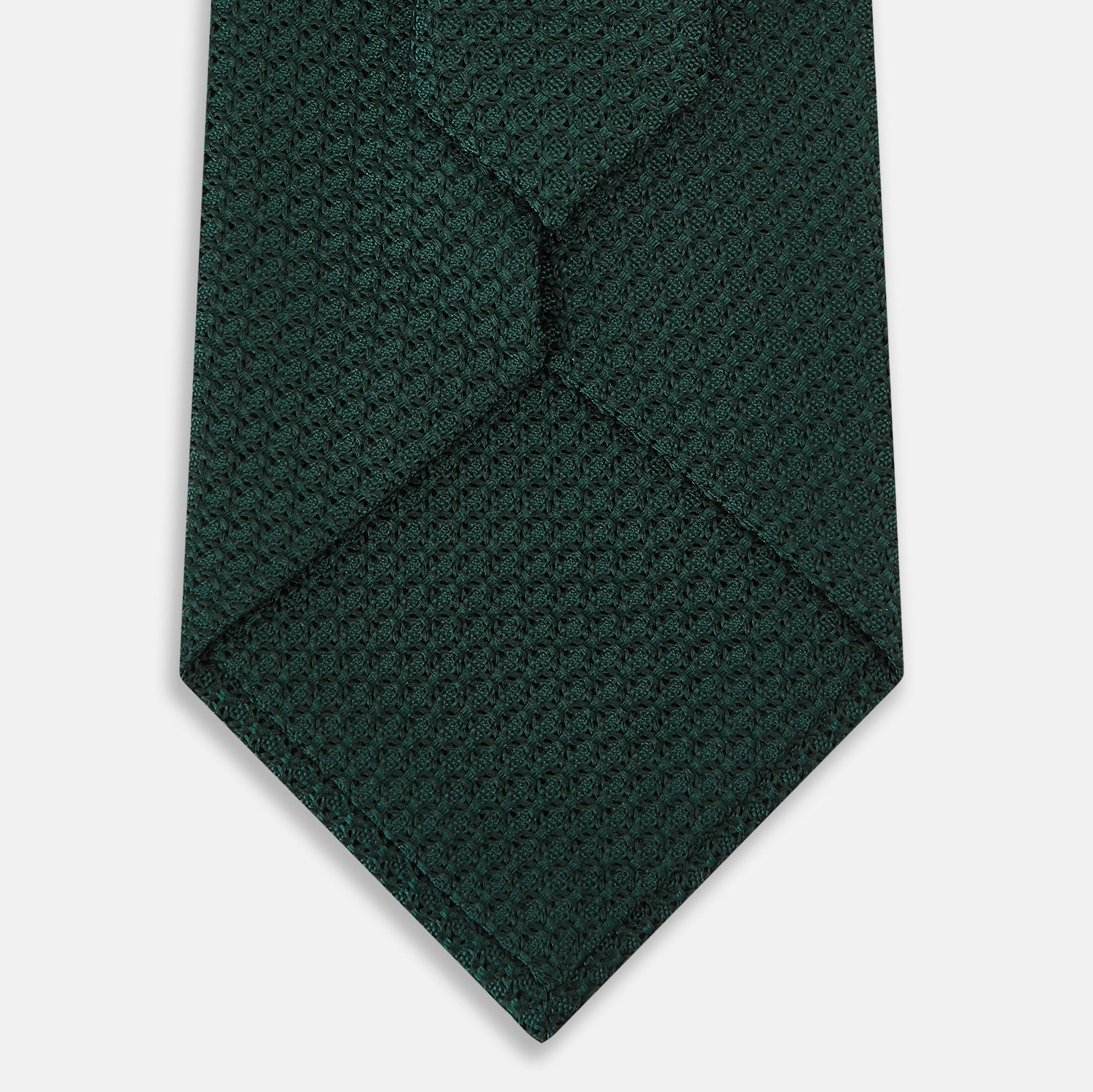 View 3 of product A Dark Green Grenadine Silk Tie by Turnbull & Asser UK, featuring a textured knit, is rolled up at one end and displayed on a white background.