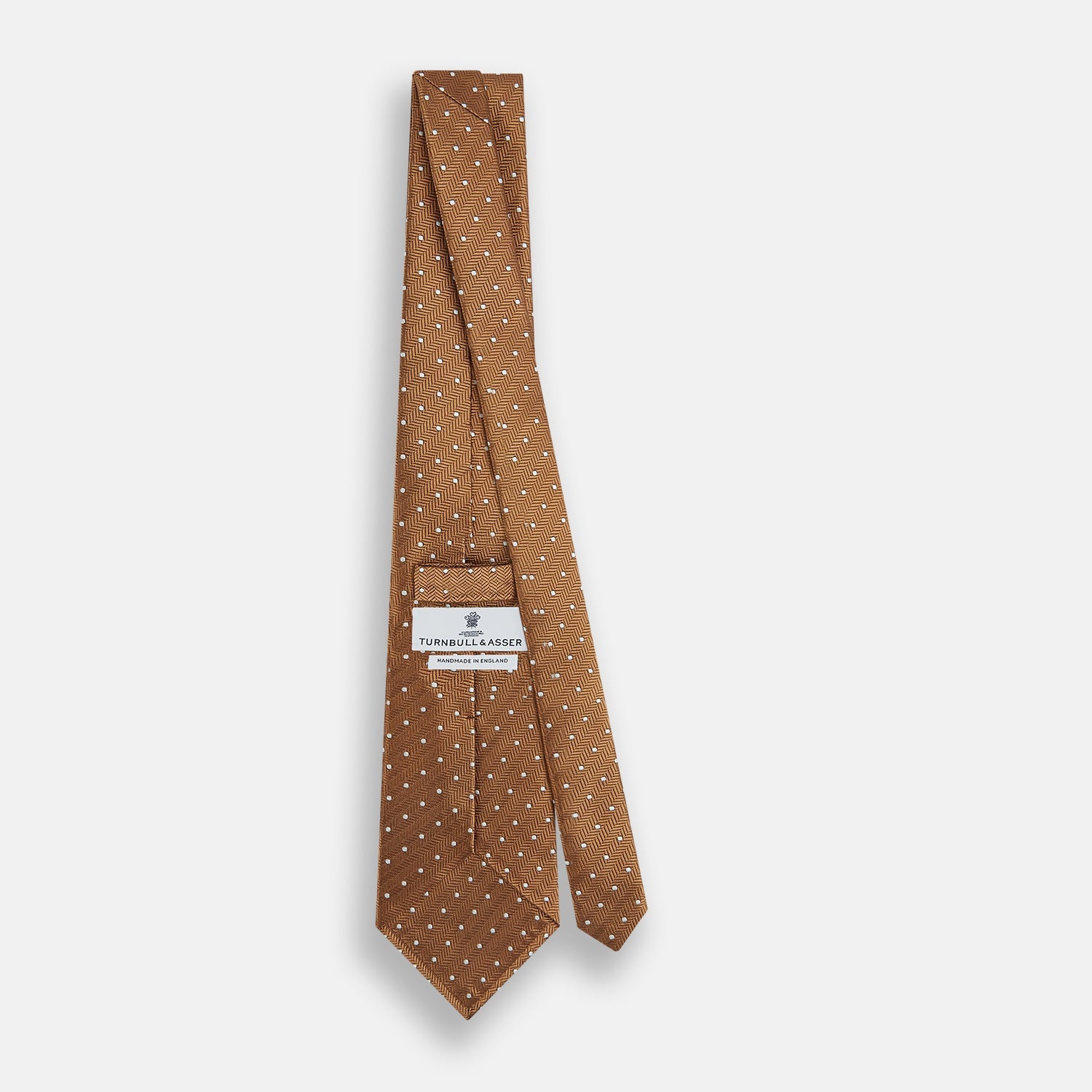 View 4 of product The Turnbull & Asser Camel and White Small Spot Herringbone Silk Tie features a stylish herringbone pattern with white spots—an elegant accessory ideal for modern office attire.