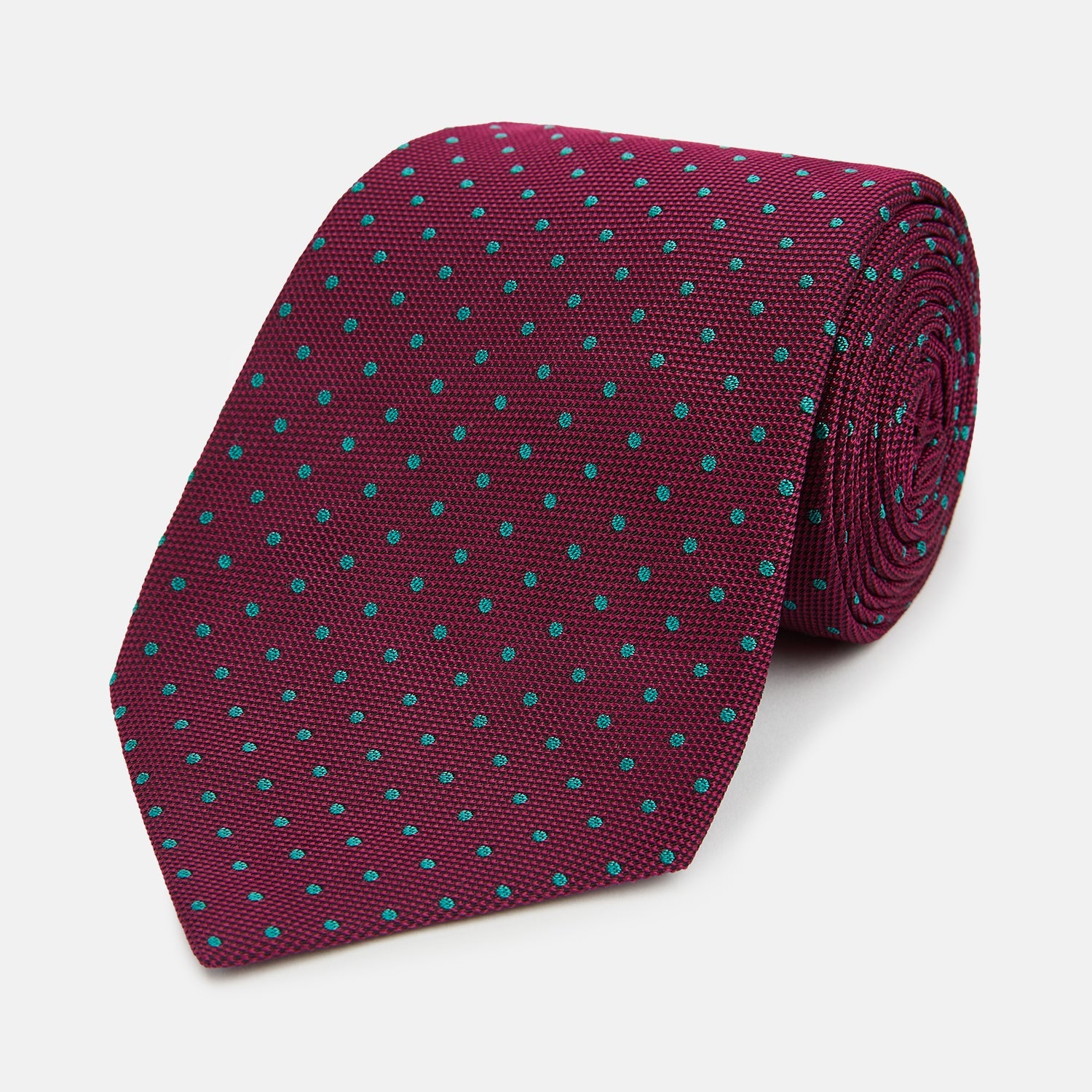 View 1 of product A rolled-up Turnbull & Asser Green and Magenta Micro Dot Silk Tie, featuring small, evenly spaced magenta dots on green silk, displayed on a plain white background—an ideal accessory for sophisticated outfits.