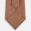View 3 of product The Turnbull & Asser Brown and White Diamond Silk Tie features a repeating small geometric pattern and is displayed rolled up on a plain white background.