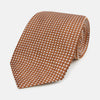 View 1 of product The Turnbull & Asser Brown and White Diamond Silk Tie features a repeating small geometric pattern and is displayed rolled up on a plain white background.