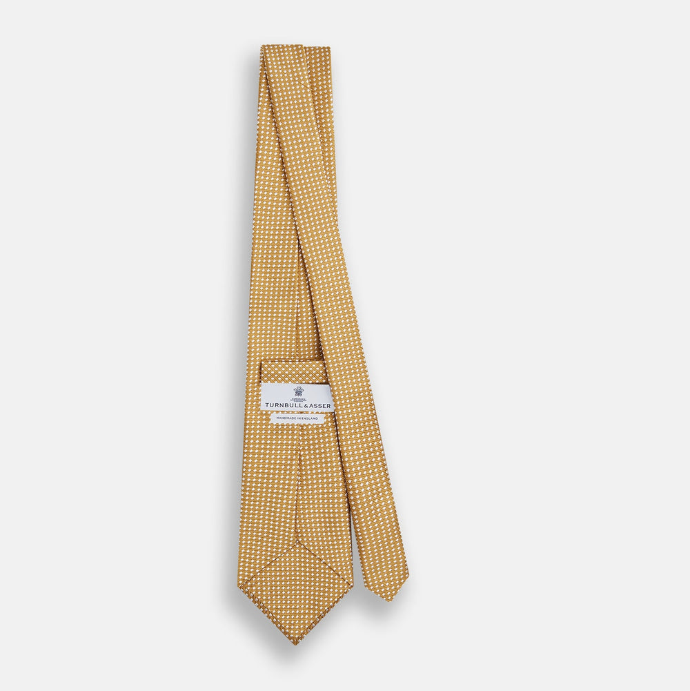 A Turnbull & Asser Light Brown and White Diamond Silk Tie, featuring a refined white geometric pattern, ideal for modern office wear, shown rolled on a plain white background.