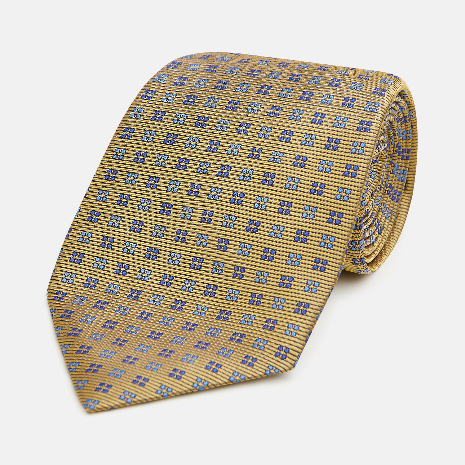 View 1 of product The Turnbull & Asser Blue and Gold Multi Dot Silk Tie features blue and gold dots in neat rows, presented rolled up on a white background.