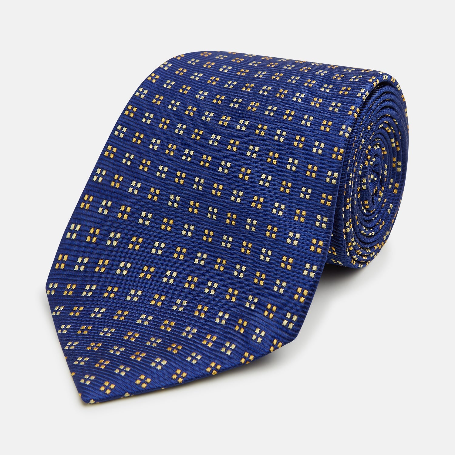 View 1 of product The Turnbull & Asser Blue and Yellow Multi Dot Silk Tie features a geometric yellow and white pattern, ideal for modern office wear. The elegant silk tie is showcased rolled up on a plain white background.
