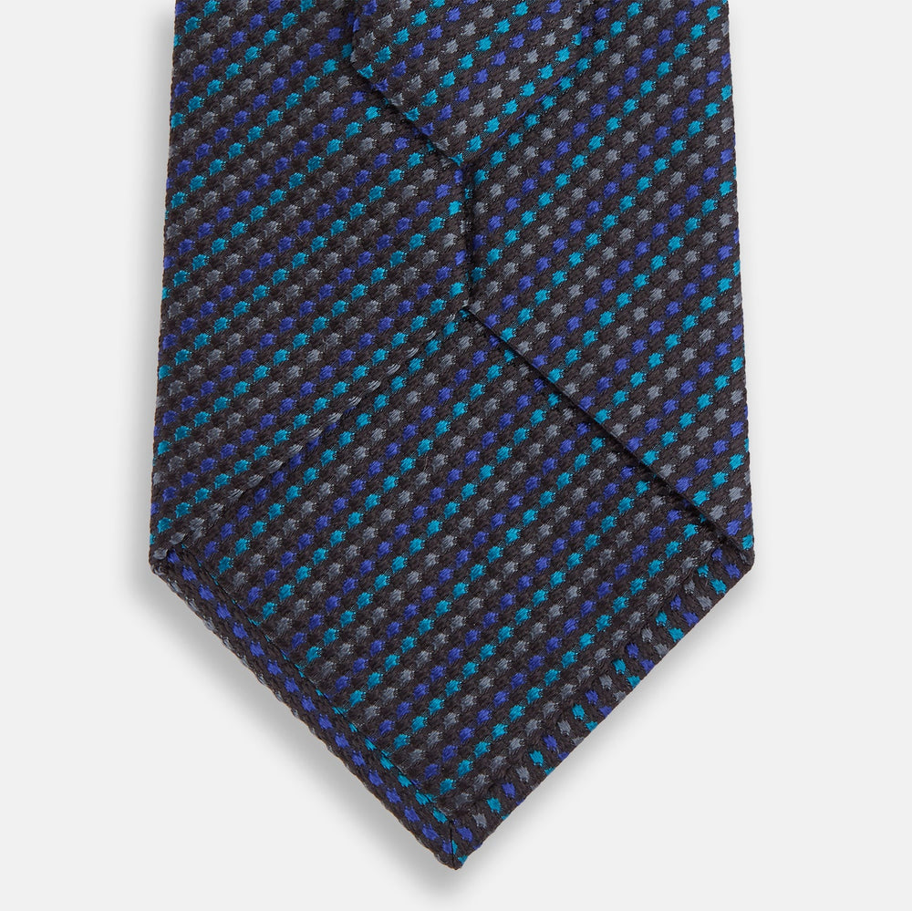 A close-up of the Turnbull & Asser Navy Multi Silk Tie, showcasing its textured design with small blue and black checks, exuding refined elegance against a plain white background.