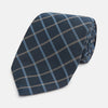 View 1 of product The Turnbull & Asser Navy Fine Double Check Silk Tie, featuring a refined navy, light blue, and tan plaid, is neatly rolled on a white background—an ideal accessory to complement any Turnbull & Asser shirt.